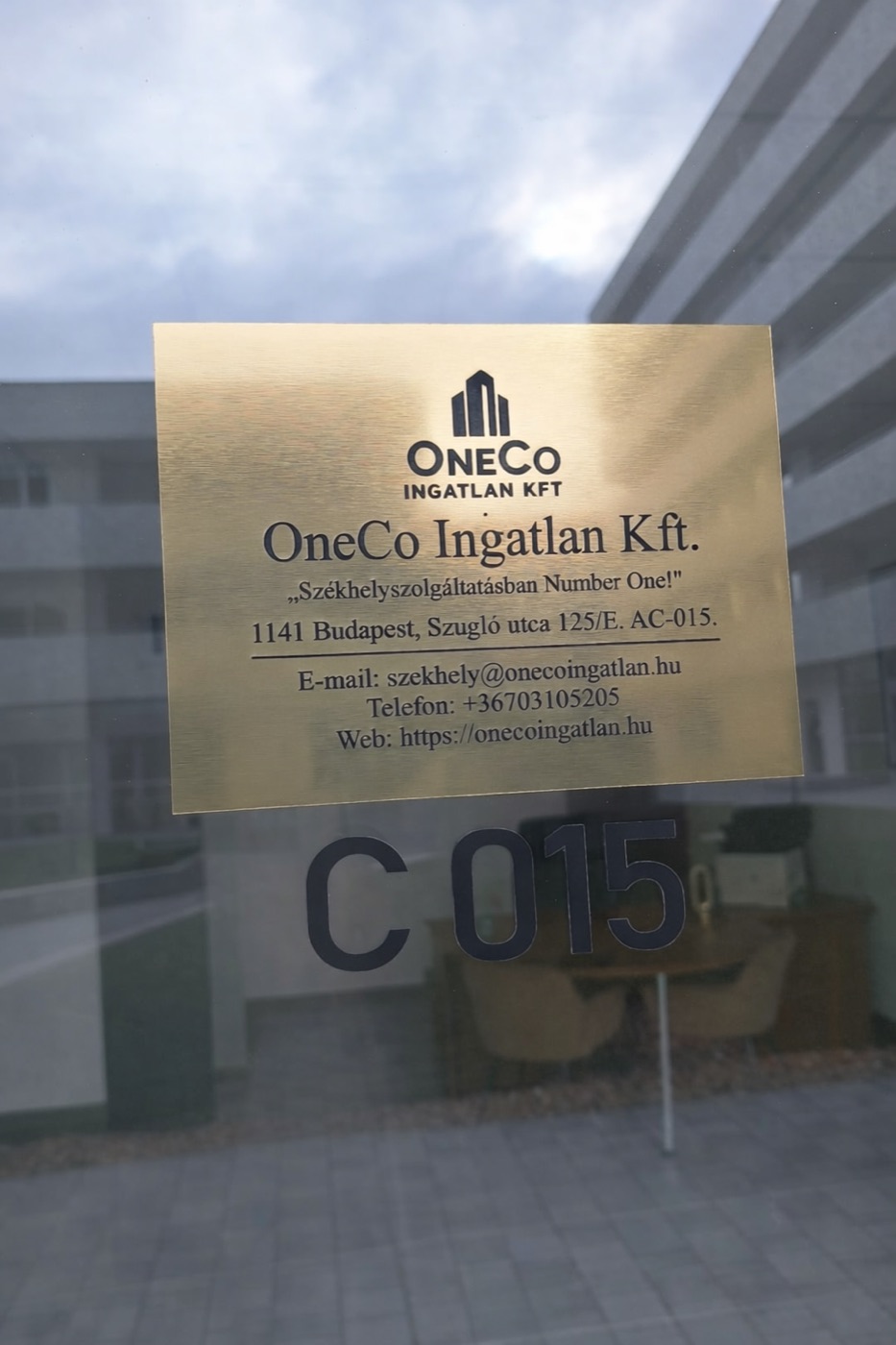 A OneCo Ingatlan Kft. cégtáblája az iroda ajtaján